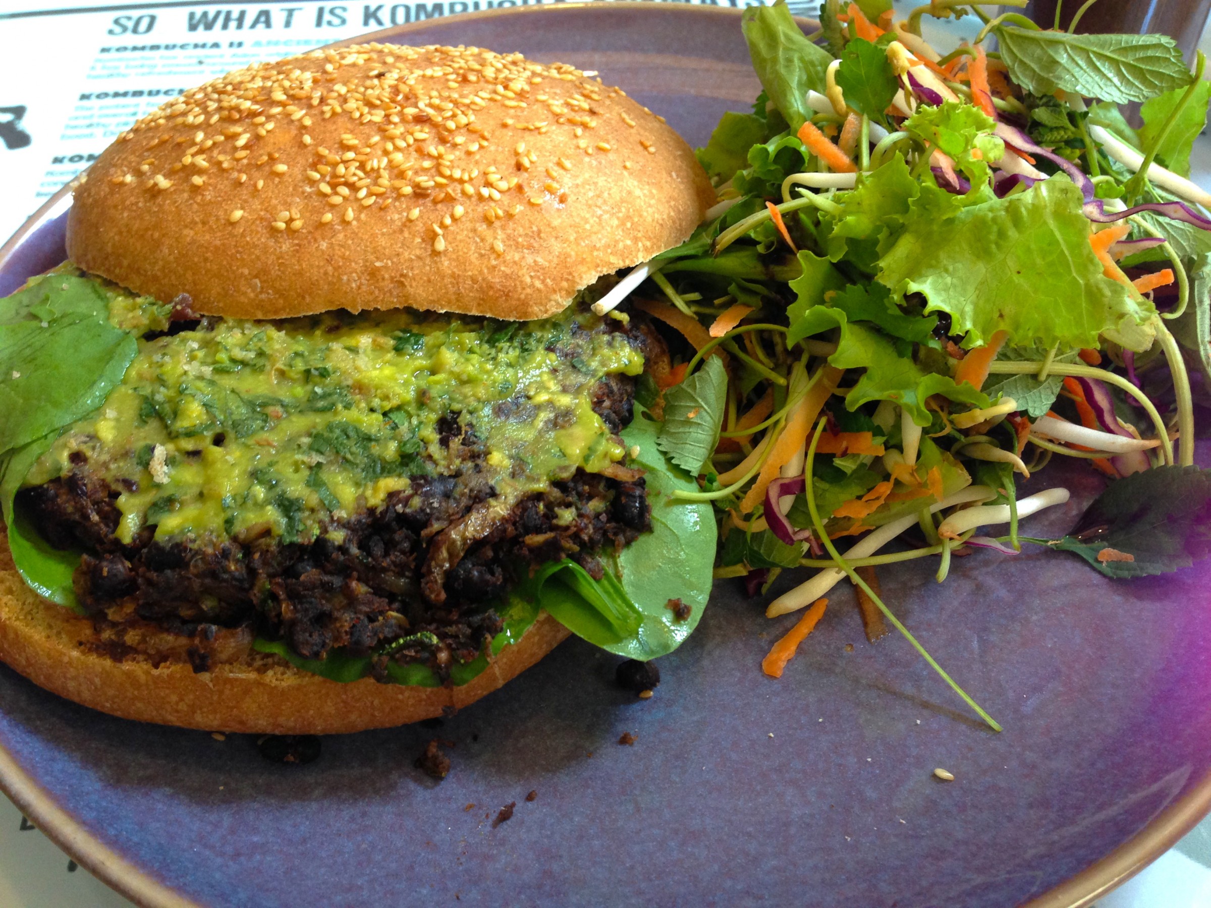 Carmelized Zucchini & Black Bena Burger. Comes with avocado and kinh gioi dressing and fresh spinach leaves on a homemade wholemeal sesame bun.